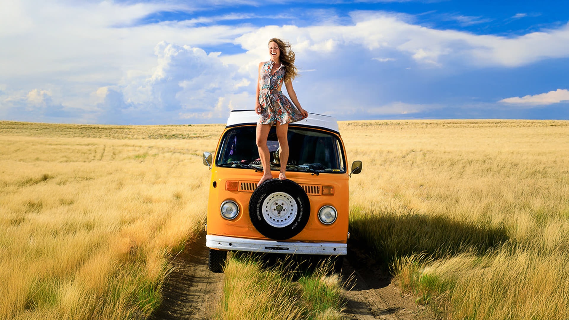 Still from The Meaning of Vanlife — a woman standing on the bonnet of an orange Kombi van in a golden field